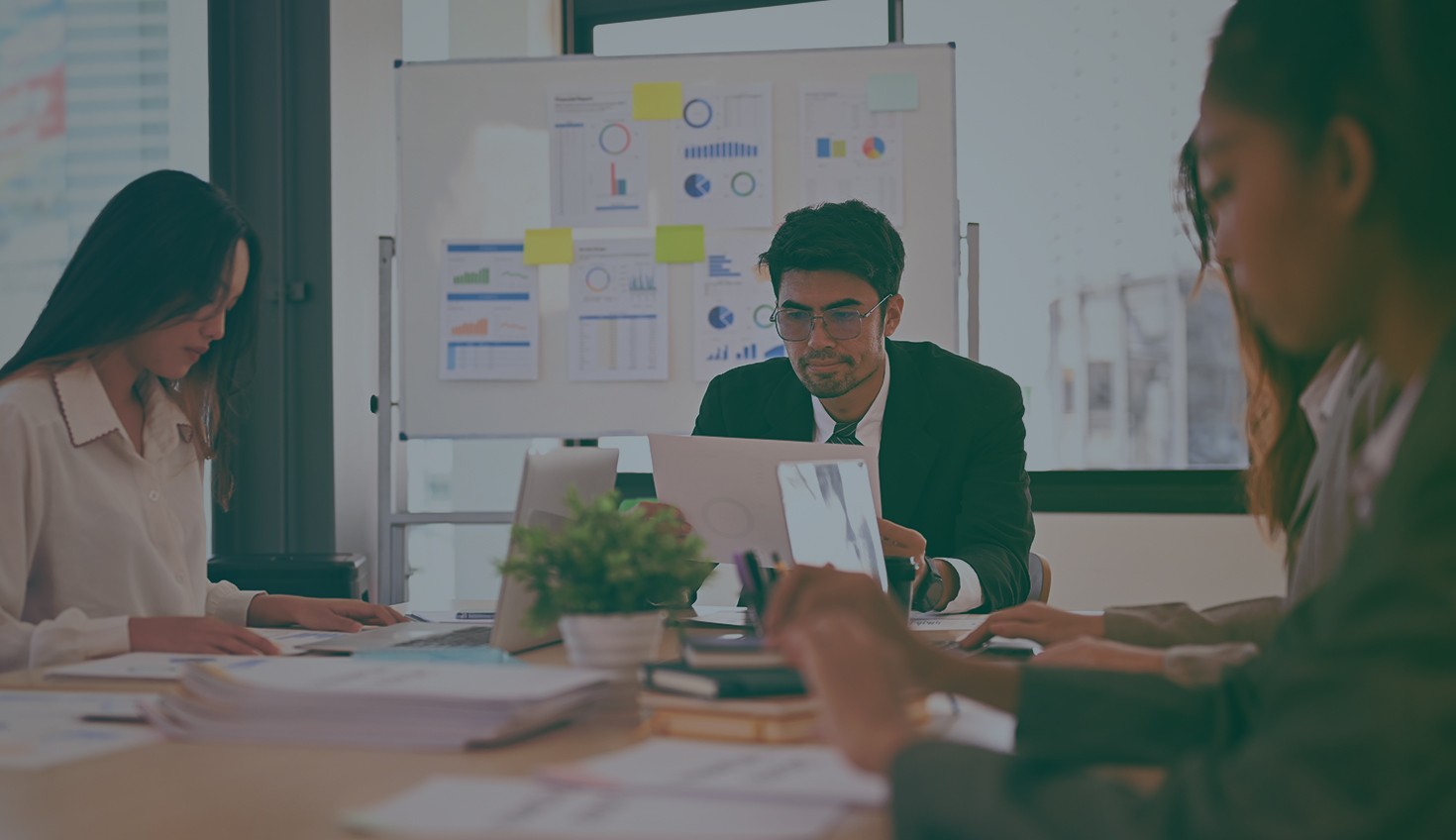 Stock image with an overlay showing a group of people working in an office with a whiteboard with infographics.