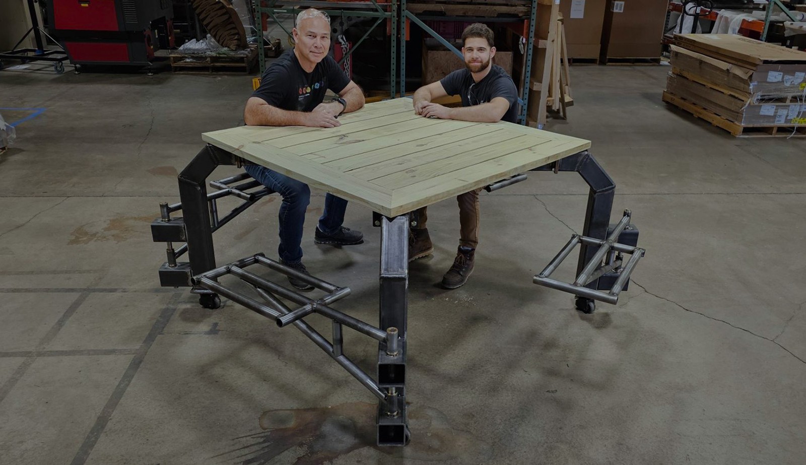 Image with an overlay showing two engineers testing out the finished inclusive picnic table.