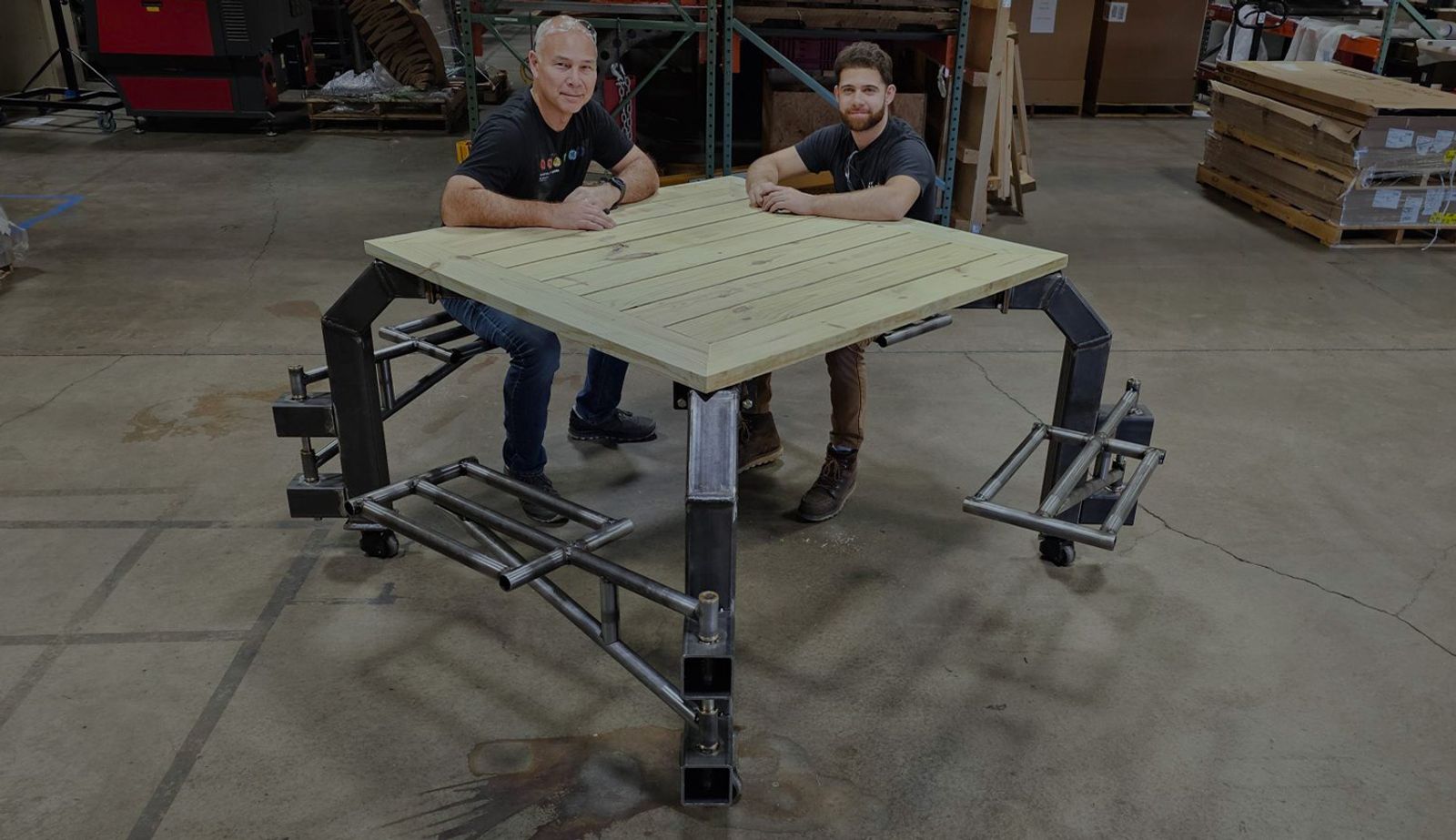 Image with an overlay showing two engineers testing out the finished inclusive picnic table.