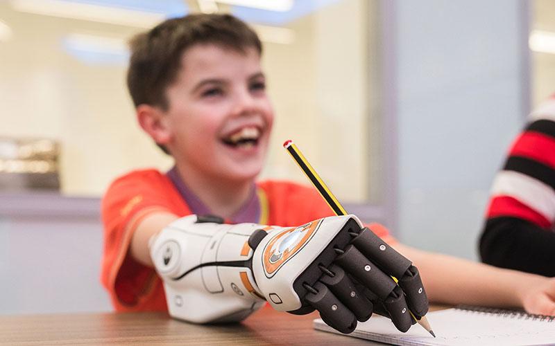 Child writing with the Open Bionics' Hero Arm