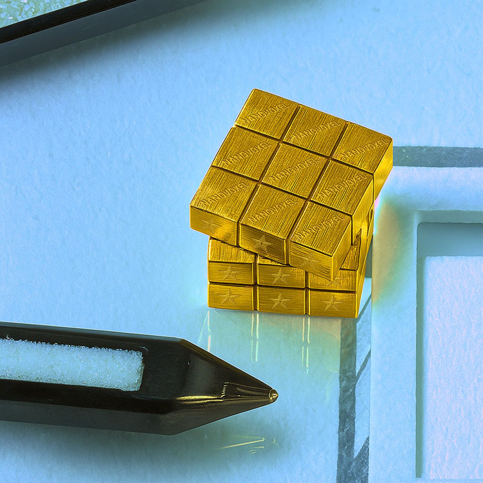 NanoVoxel’s design of a 3D cube, designed in Onshape, compared to the size of a pen tip. 