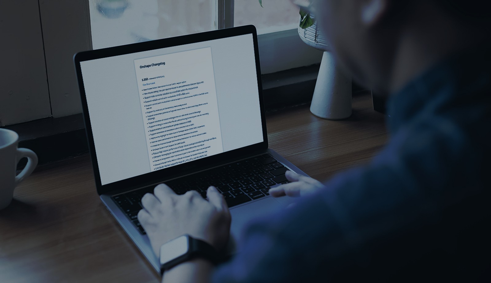 Stock image with an overlay showing a person using a laptop with the Onshape Changelog on the screen.