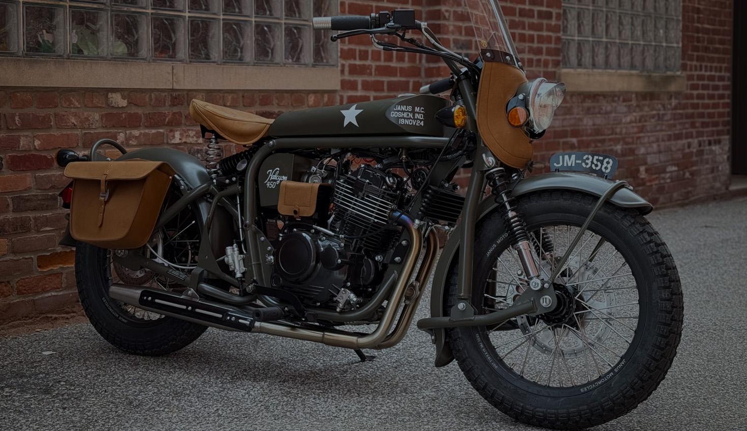 Darkened header image showing a Janus Motorcycle parked next to a brick building.