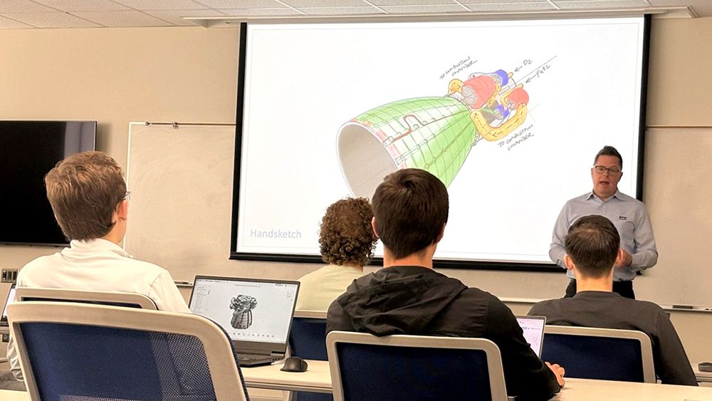 Picture showing an educator in front of a CAD model lecturing students in a STEM classroom.