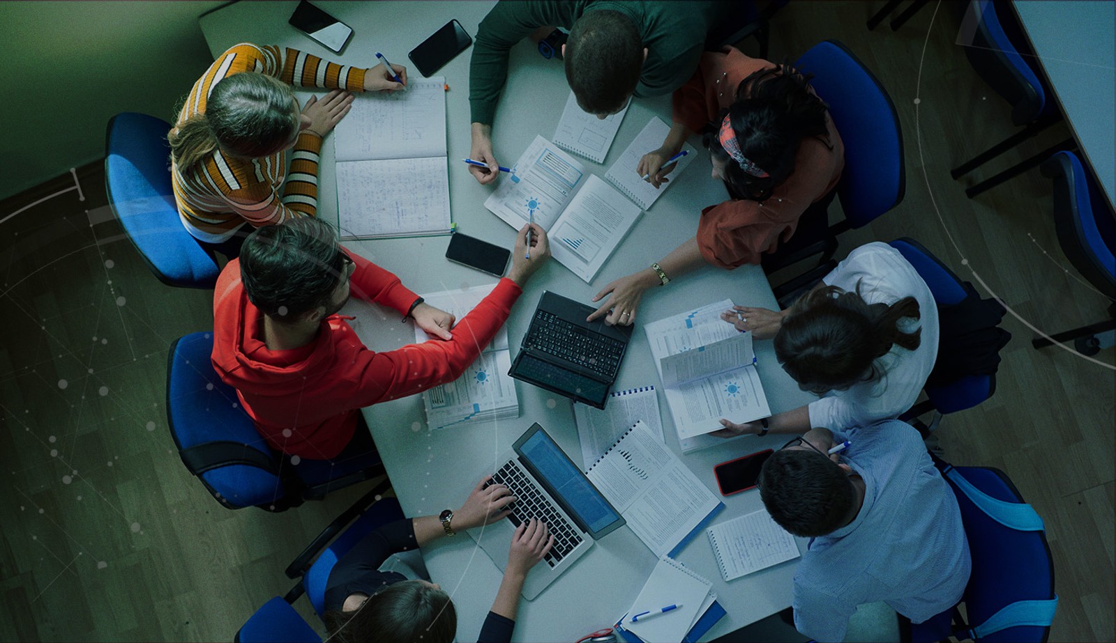 Stock image with an overlay showing students at at desk with assignments and laptops.