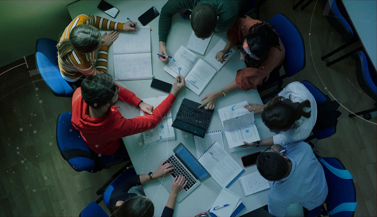 Stock image with an overlay showing students at at desk with assignments and laptops.