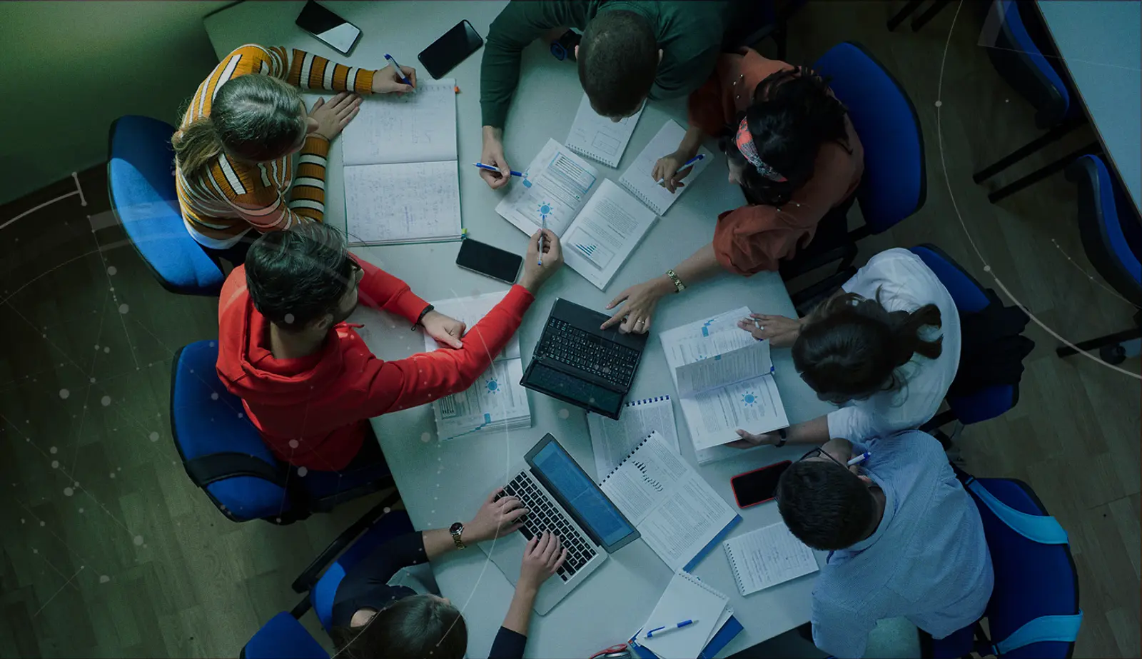 Stock image with an overlay showing students at at desk with assignments and laptops.