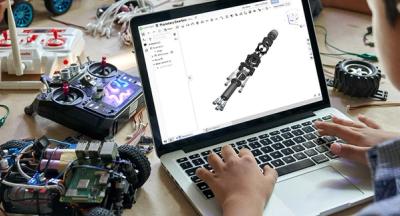 A student designing in Onshape surrounded by robotics parts. 