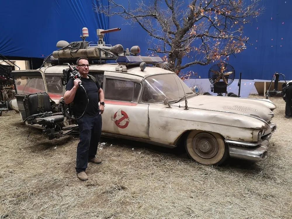 ben eadie standing in front of a ghostbusters car