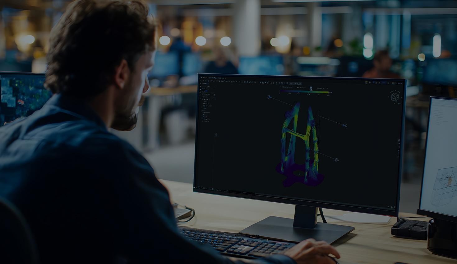 Darkened header image showing a man using a computer to do simulation testing on CAD model.